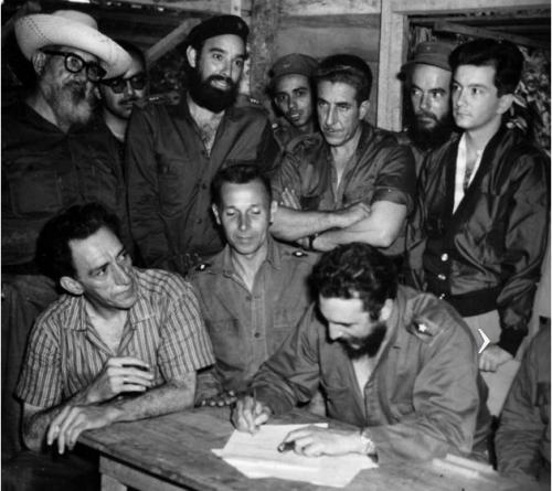 El Comandante en Jefe Fidel Castro firma la Ley de Reforma Agraria en la Comandancia de La Plata. A su derecha el médico Comandante Julio Martínez Páez, ministro de Salubridad, y Manuel Fernández, ministro de Trabajo. De pie, de izquierda. a derecha, el Comandante Crescencio Pérez, el Capitán Antonio Núñez Jiménez, el médico Comandante Manuel (Piti) Fajardo, Luis Orlando Rodríguez, ministro de Gobernación, el médico, Comandante René Vallejo, y el doctor Armando Hart Dávalos, ministro de Educación.